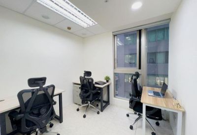 Internal three-person office suite with light wood desks and city views.