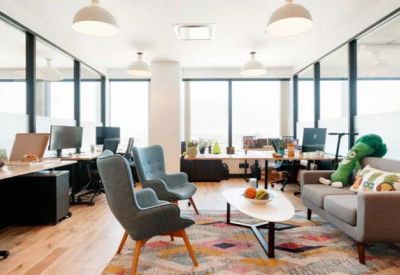 Open-plan office space with private glass booths, ergonomic chairs, and a colorful patterned rug.