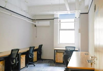Private office space with wooden desks, ergonomic chairs, and a large window for natural light.