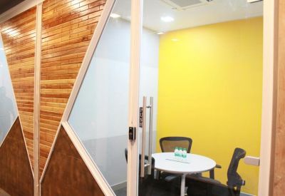 Small private meeting room with a yellow feature wall and glass door.