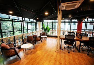 Bright coworking area with varied seating and large windows overlooking greenery.