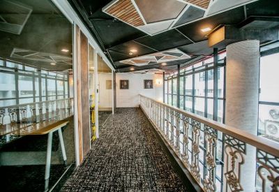 Industrial-style balcony workspace with glass railings and dark wood flooring.
