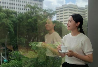 Woman enjoying a cup of coffee by a window with city views