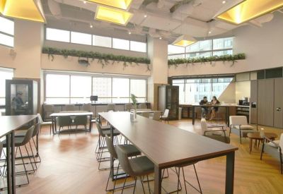 Open-plan workspace with long communal desks and comfortable grey chairs.