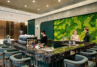 Sleek marble cafe bar with a vibrant green moss feature wall and modern teal seating.