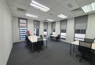 Spacious open-plan workspace with multiple white desks and ergonomic chairs near windows.