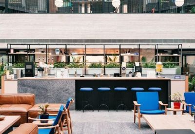 Communal break area with a stone-topped bar, blue stools, and leather lounge seating.