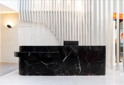 Modern reception area with a dark marble desk and vertical slat wall feature.