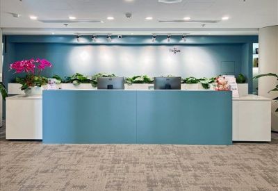 Reception area with a blue desk and decorative plants.