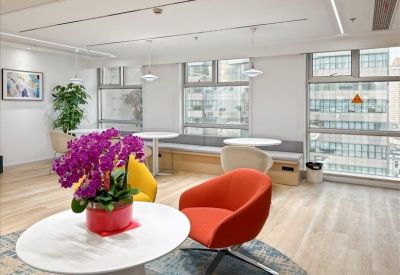 Lounge area featuring vibrant orange chairs and a bright floral centerpiece.