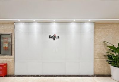 Reception area with a sleek white branded wall and warm stone flooring.