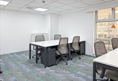 Bright shared office space with grey ergonomic chairs and white desks.
