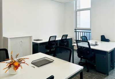 Shared office space with multiple white desks and black mesh chairs.