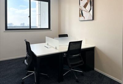 Two-person private office suite with white desks, black ergonomic chairs, and large window.