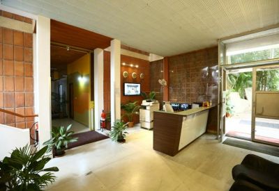 Bright reception lobby with a dark wood desk and potted indoor plants.