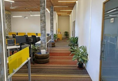 Open-plan office hallway with striped carpeting and ceiling track lighting.