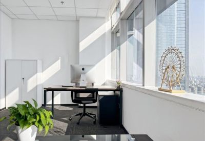 Bright private office featuring a desk with a computer monitor and a decorative ferris wheel model.
