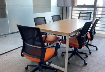 Meeting room with a light wood table and orange-accented ergonomic chairs.