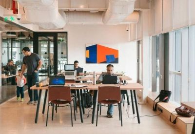 Open-plan office with desks, laptops, and large windows.