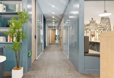 Narrow office corridor with glass partitions and a glimpse into a meeting room.