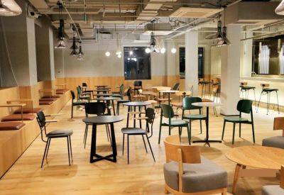 Communal coworking lounge with wooden tiered seating and variety of bistro tables.