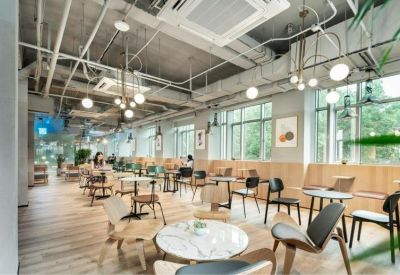Bright communal cafe area with industrial ceilings and diverse modern seating options.