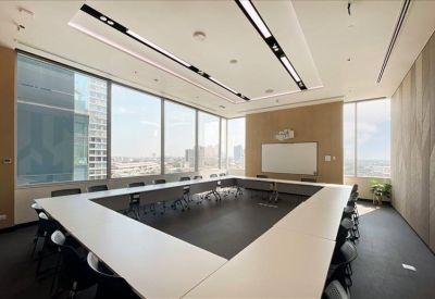 Spacious boardroom with a U-shaped white table and large windows.