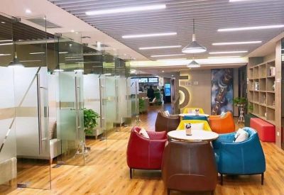 Bright breakout area with vibrant red and blue lounge chairs and glass-partitioned private booths.