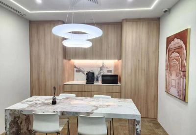 Modern communal kitchen and dining area with warm wood cabinetry and a marble table.