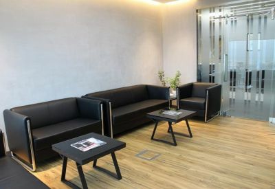 Casual waiting area with black leather sofas and light wood flooring.