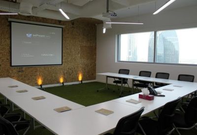 Meeting room with U-shaped table and green turf feature wall.