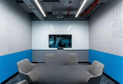 Minimalist meeting room with blue wainscoting and a wall-mounted video conferencing screen.