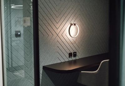 Close-up of a textured grey acoustic wall panel with a circular feature light.