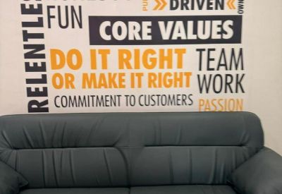 Reception lounge with a grey sofa and core values wall art.