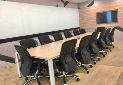 Large boardroom featuring a light wood table, black chairs, and a white presentation wall.