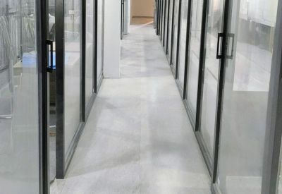 Modern office corridor lined with glass partitions and black frames.