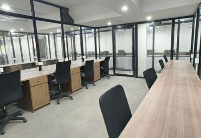 Coworking area featuring long wooden desks and black ergonomic chairs.