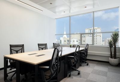 Conference room with a light wood table, ergonomic black mesh chairs, and floor-to-ceiling windows.
