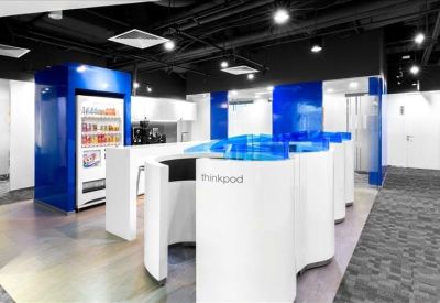Contemporary breakout area featuring white curved desks and blue glass partitions.