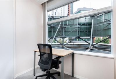 Private window office with a mesh chair and desk overlooking urban infrastructure.
