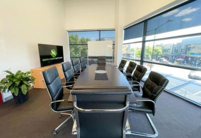 Large boardroom with a long black table, many leather chairs, and floor-to-ceiling windows.