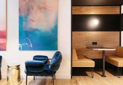 Cozy semi-private booths and velvet armchairs next to large abstract paintings.