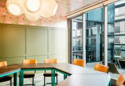 Vibrant meeting room with a U-shaped wooden table, green accents, and a patterned ceiling.