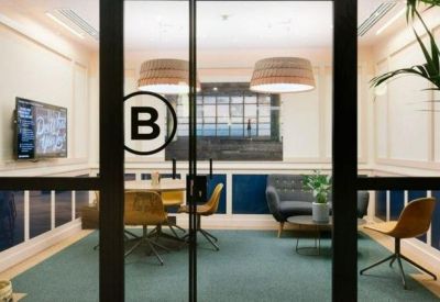 Private glass-walled meeting room with a round table and comfortable seating.