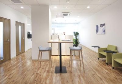 Communal breakout area with a high table, stools, and green lounge seating.