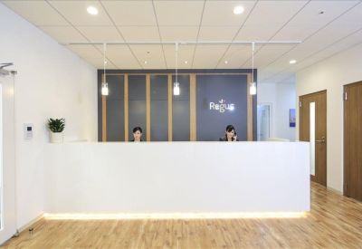 Minimalist white reception desk with wood flooring and overhead lighting.