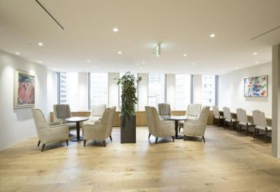 Sunlit breakout area featuring diverse seating arrangements, large windows, and warm wood floors.