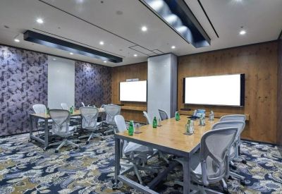 Spacious meeting room with two wooden tables and patterned blue carpet.