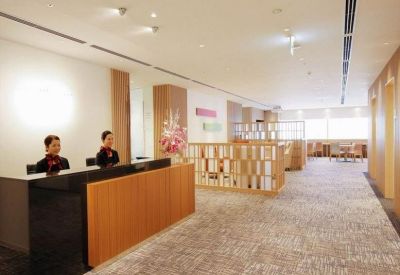 Reception area with a wooden desk, staff in uniform, and a floral arrangement.