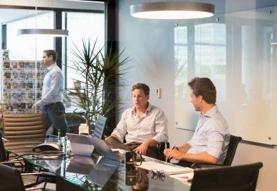 Professional meeting room with a glass-top table, leather chairs, and large windows with natural light.